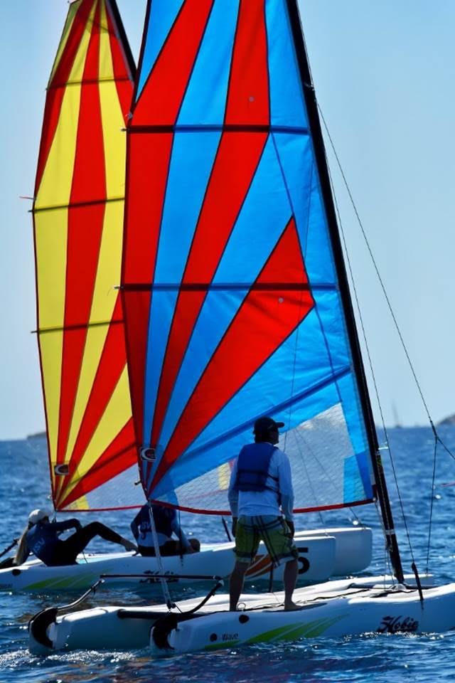 St. Thomas' Chris Curreri, winner of the Hobie Wave class, standing foreground on his OT the App on day 3 of the 50th St. Thomas International Regatta photo copyright Dean Barnes taken at St. Thomas Yacht Club and featuring the Catamaran class