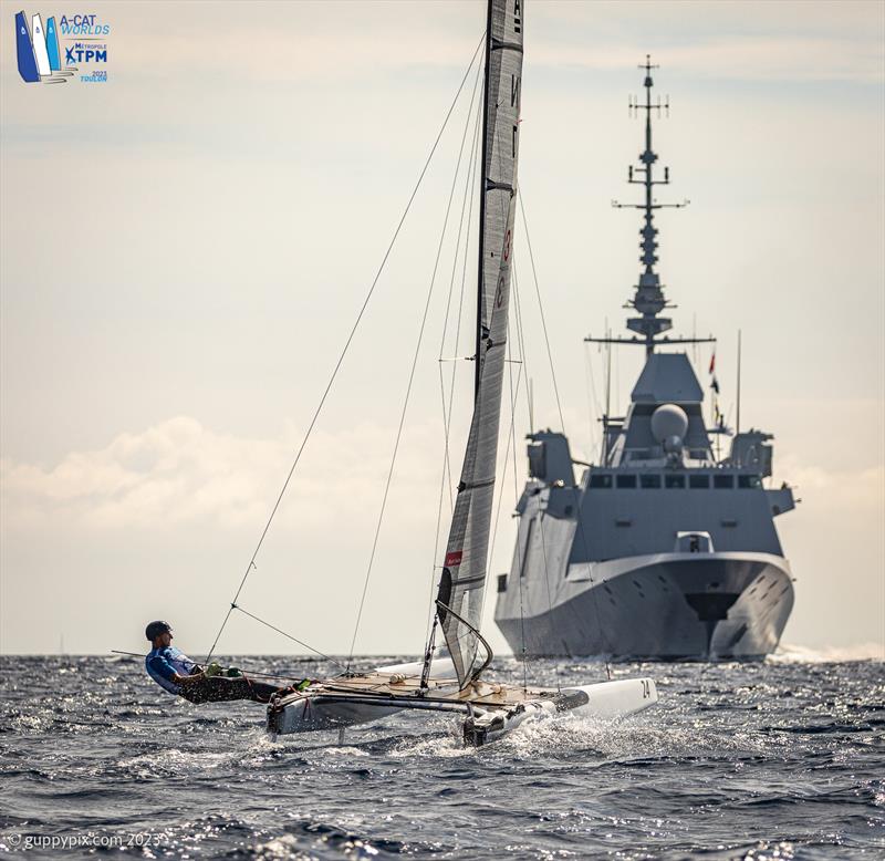 A-Cat Worlds at Toulon, France Day 5 - Jan Saugman DEN 3 commences his Viking attack on an Aquitaine-Class French frigate. But the only horns came from the frigate to reminding him they were there and thus a diplomatic incident was averted photo copyright Gordon Upton / www.guppypix.com taken at Yacht Club de Toulon and featuring the A Class Catamaran class