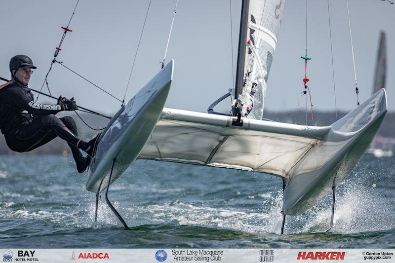 Australian A-Cat Nationals on Lake Macquarie Day 3 - Ron Scherwinsk gets a little airtime at the bottom mark photo copyright Gordon Upton / www.guppypix.com taken at South Lake Macquarie Amateur Sailing Club and featuring the A Class Catamaran class