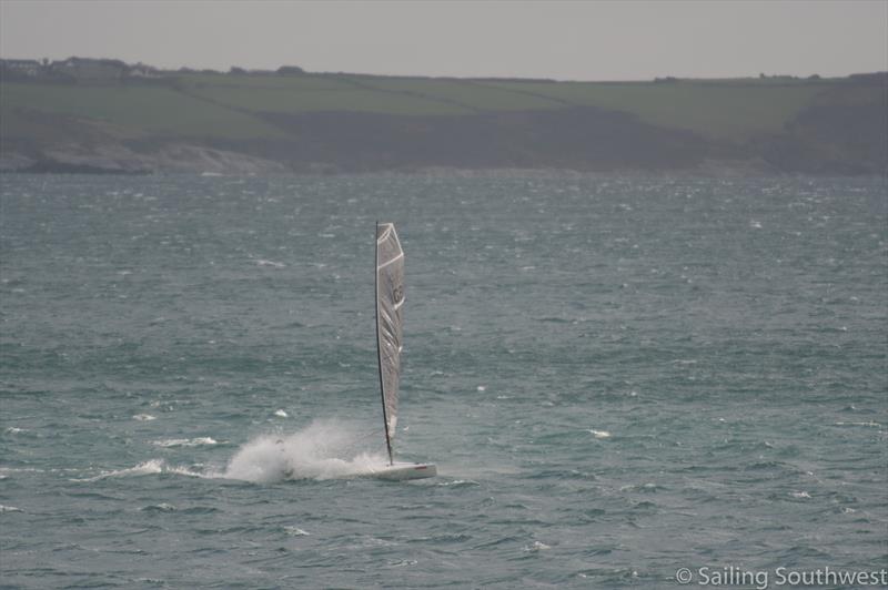 Kian Andrews battling winds nearly 40 knots, accompanied by Pierre the dolphin photo copyright Lottie Miles / Sailing Southwest taken at Penzance Sailing Club and featuring the D-Zero class