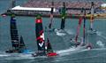 The fleet led by ROCKWOOL Denmark SailGP Team ahead of BONDS Flying Roos SailGP Team and Red Bull Italy SailGP Team round the finish marker in front of the grandstand full of spectators at The Rolex SailGP Championship ITM New Zealand Sail Grand Prix