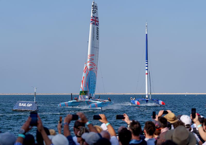 Spectators watch on as Great Britain SailGP Team helmed by Ben Ainslie and France SailGP Team helmed by Quentin Delapierre sail closely past the Race Village on Race Day 2 of the Dubai Sail Grand Prix presented by P&O Marinas - photo © Joe Toth for SailGP