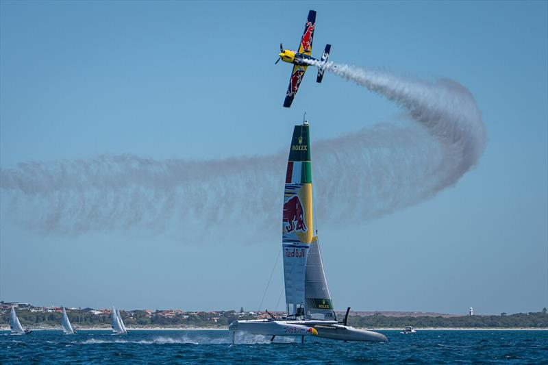 A Red Bull stunt aeroplane flies close to the Red Bull Italy SailGP Team F50 catamaran during a practice session ahead of the ORACLE Perth Sail Grand Prix in Perth, Australia photo copyright SailGP / Red Bull Content Pool taken at  and featuring the F50 class