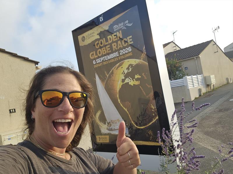 Daniel Pinsky's manager, Michal, gives an enthusiastic thumbs-up beside one of the official GGR 2026 posters now appearing across Les Sables-d'Olonne, as the host city prepares to welcome the fleet for the race start on 6 September - photo © Michal Arbel