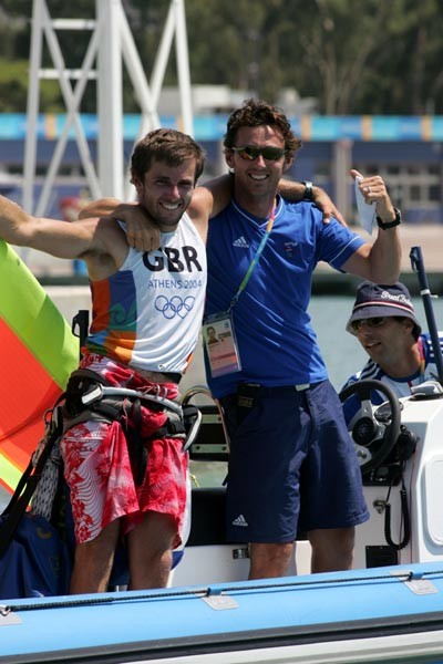 Nick Dempsey celebrates with coach Barry Edgington after winning bronze in the men's windsurfing class photo copyright Richard Langdon taken at  and featuring the IMCO class