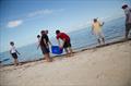Ben Moon and Jason Carroll carry the bin as racers scour the beach for bottles, cans, and other trash, ensuring that the Moth Class 'leaves no trace' when it departs Key Largo © Meredith Block / US Moth Class