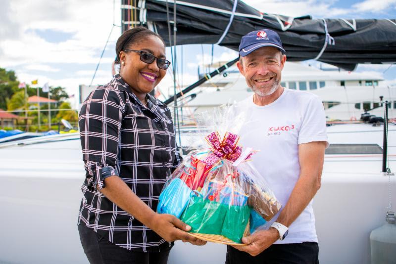 A welcome basket of Grenadian specialities is handed over to Kuka3's owner on arrival by Chinel Sandy from the Grenada Tourism Authority - 2018 RORC Transatlantic Race - photo © RORC / Arthur Daniel