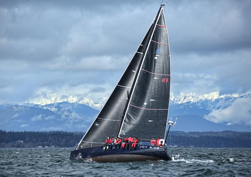 Joy Ride flashes her undercarriage as Washington State's Olympic Mountains flash their snowy slopes through the clouds photo copyright Jan's Marine Photography taken at Seattle Yacht Club and featuring the J/122 class