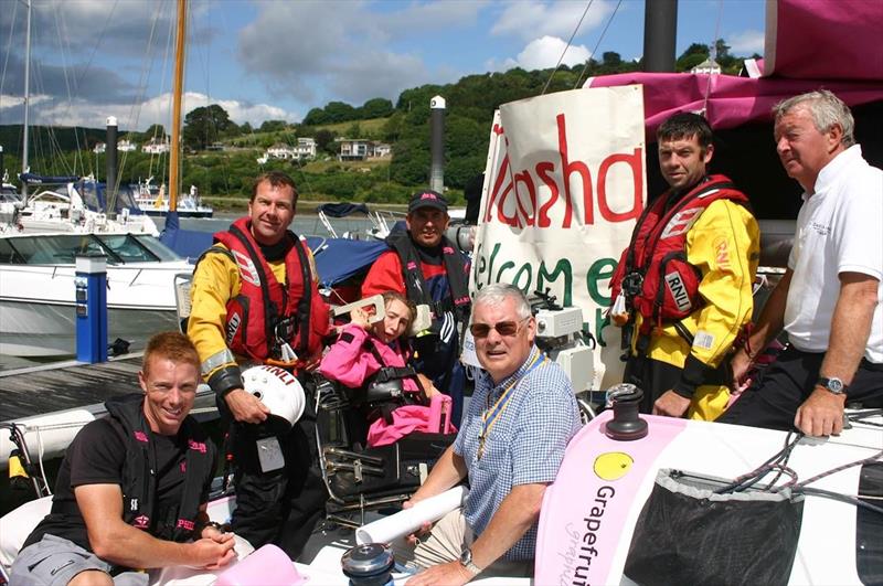 Peter Goldstraw from The Rotary Club of Dartmouth (centre) prepares to present Natasha with a cheque as she is welcomed to Dartmouth by the RNLI Dart Lifeboat and Dart Sailability, Dad Gary and coach Phil Devereux watch on photo copyright Anne Bailey / Dart Sailability taken at  and featuring the Mini Transat class