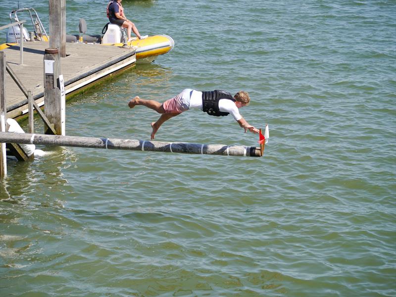 Charlie Dixon getting the flags on the greasy pole during Regatta Day at Blackwater Sailing Club Club Week 2022 photo copyright Peter Gould taken at Blackwater Sailing Club