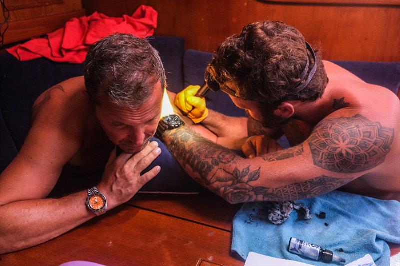 Always time for tattoos at sea! Sam working his magic on a very brave Dane - McIntyre Ocean Globe Race photo copyright OGR2023 / Godspeed / Skeleton Crew / Emma Walker taken at  and featuring the Ocean Globe Race class