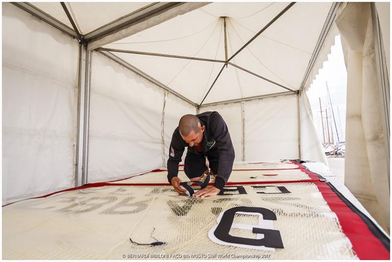 John McAfee putting numbers on a sail at the Musto Skiff Worlds - photo © Bernardi­ Bibiloni