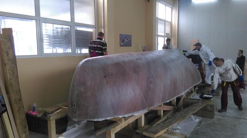 Croatian Gajeta build - cloth is hand positioned and epoxy rolled onto it, then squeegeed off - photo © West System International